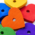 Colorful wooden heart-shaped bird toy parts for parrot enrichment, featuring red, blue, yellow, orange, green, and purple pieces.