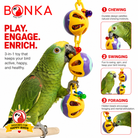 Green parrot playing with Bonka 3-in-1 bird toy featuring chewing, swinging, foraging with colorful plastic balls and beads